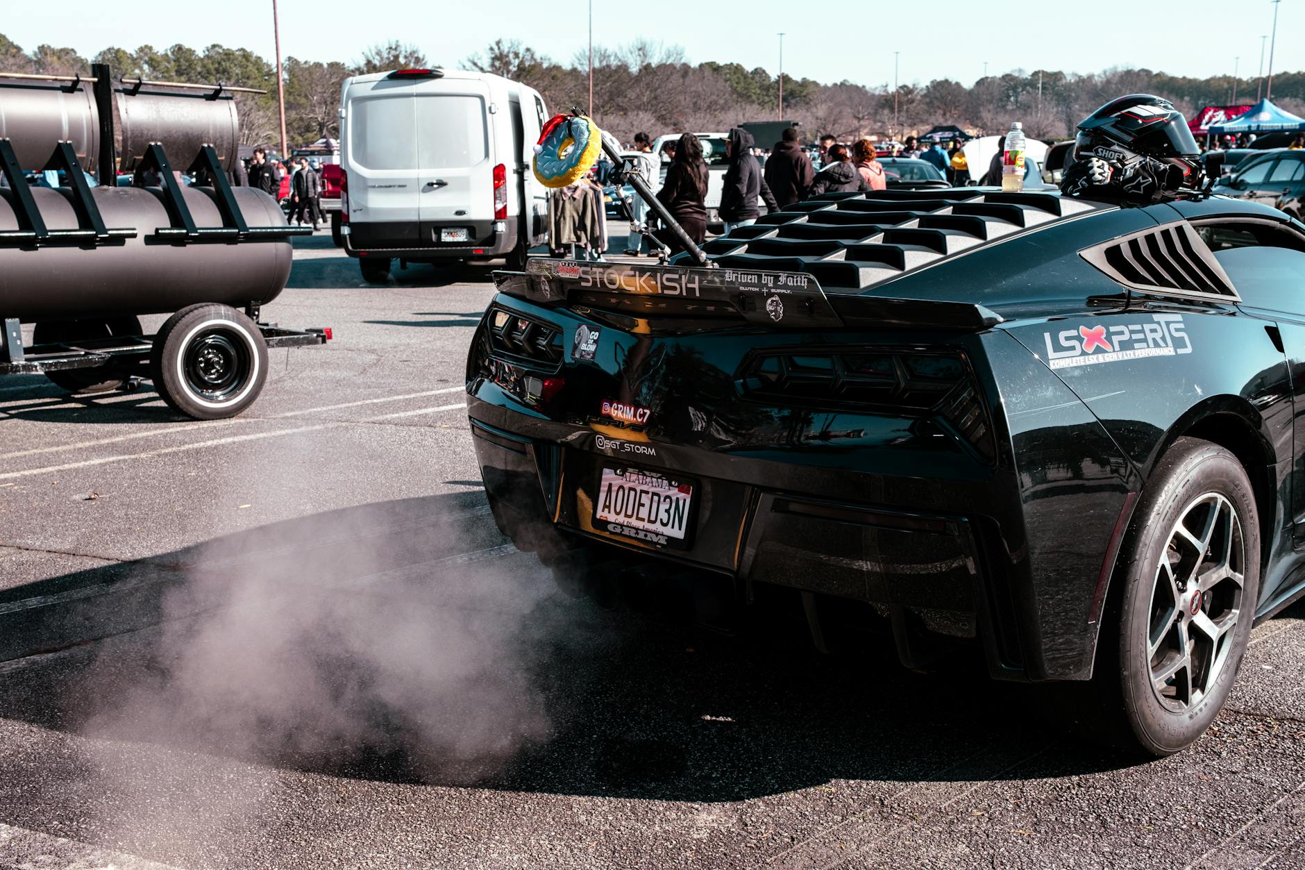 A powerful race car releasing exhaust smoke in an outdoor auto event gathering.