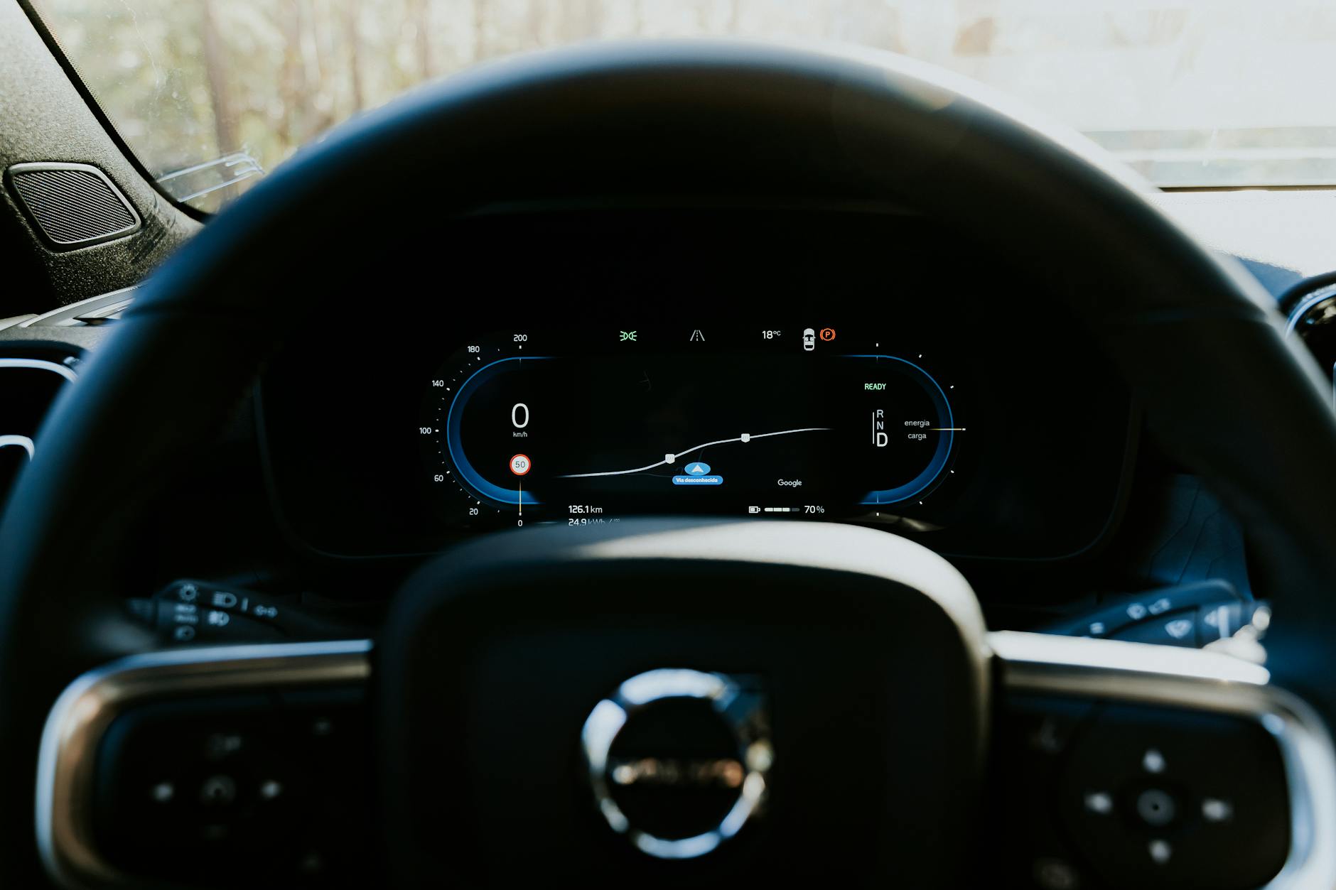 Close-up of a Volvo car steering wheel with digital dashboard display, showcasing modern automotive technology.