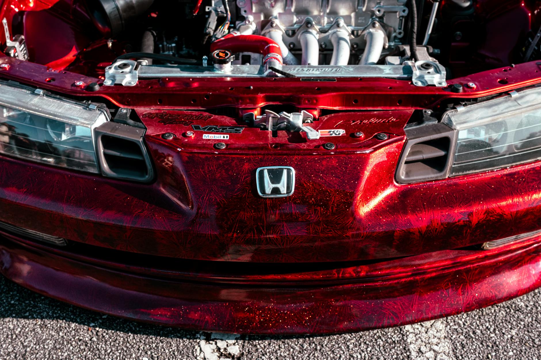 Vibrant photo of a red car hood with custom engine detailing and metallic paint.